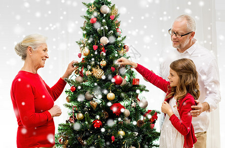 家庭在家中装饰圣诞树时微笑的家庭 孩子 装潢图片