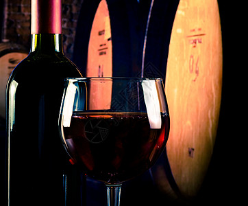 在旧酒窖背景上靠近瓶子的红葡萄酒杯 带有文字空间 增值税 城堡图片