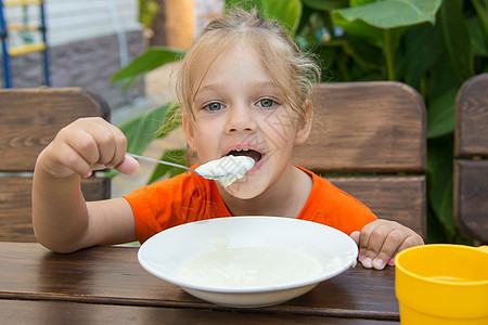 有趣的5岁女孩 快乐的五岁女孩 吃粥早餐背景图片