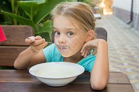 6岁女孩快乐地吃粥早餐的饭图片素材