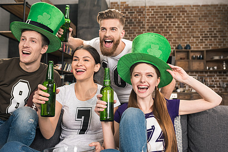 带着绿色帽子快乐的年轻朋友喝酒喝啤酒 庆祝圣节节日背景图片