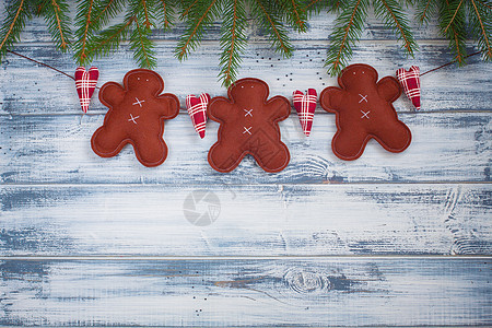 手工生姜人和圣诞树枝 在木制背景上做成的图片