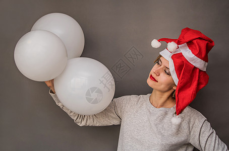穿着圣塔帽的欧洲年轻女青年 灰色背景树白气球背景图片