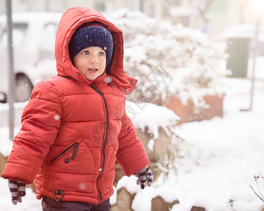 雪下时穿红色夹克和帽子的男孩图片