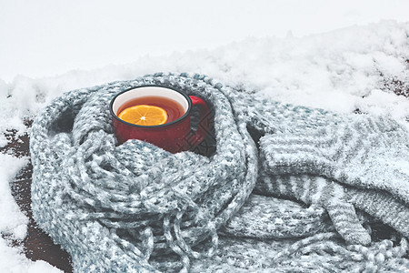 红名的热茶杯 加柠檬 在雪地木制桌椅上用丝织围巾包着柠檬 羊毛 咖啡图片
