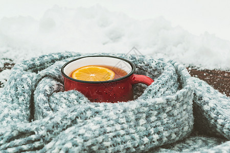 红名的热茶杯 加柠檬 在雪地木制桌椅上用丝织围巾包着柠檬 温暖的 照片图片