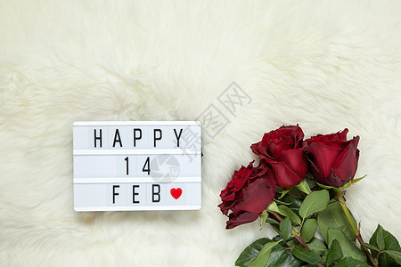 牛奶白色毛皮地毯上的栗色玫瑰花束 灯箱上刻有 Happy 14 FEB 这意味着情人节 平躺 顶视图 2 月 14 日庆祝概念 图片