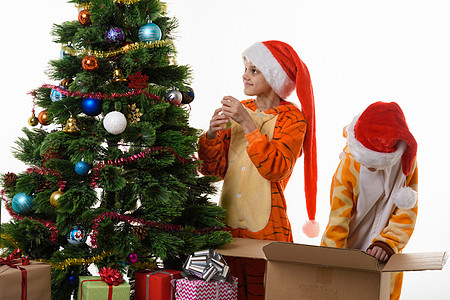 女孩装饰圣诞树 其中一人钻进一个装有玩具的盒子里背景图片