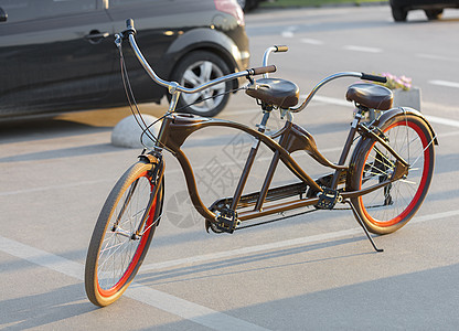 傍晚的阳光下 一辆带有猩红色轮辋的双人自行车停在停车场 下午 闲暇图片