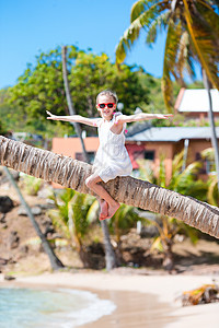 坐在棕榈树上快乐的孩子 在白沙滩的卡比巴人度假图片