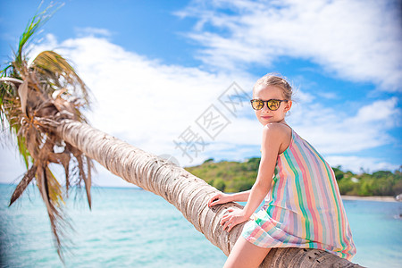 在白沙滩暑假期间坐在棕榈树上 可爱的小可爱女孩 海滨 海岸线图片