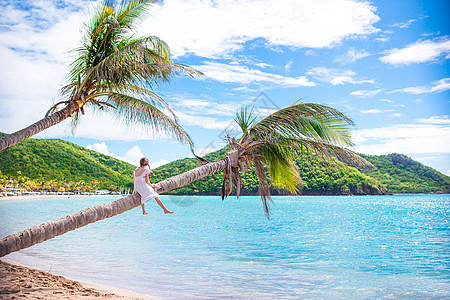 在白沙滩暑假期间坐在棕榈树上 可爱的小可爱女孩 照片 加勒比图片