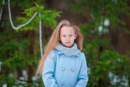 穿着蓝色大衣和手套的小可爱女孩的肖像 在寒冷的冬天户外 站在被装饰的圣诞树旁边 快乐 喜悦图片