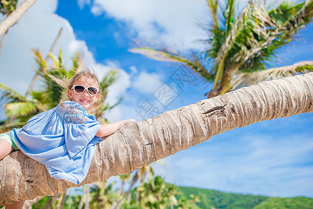 在白沙滩暑假期间坐在棕榈树上 可爱的小可爱女孩 孩子 美丽的图片