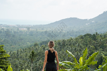 穿着黑色 T 恤的女人的背面 享受热带森林与红树林的景色 蓝天上的群山和白云 热带暑假度假概念 夏天 放松图片