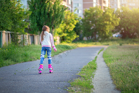 夏天 一个小女孩在沥青上骑着粉红色溜冰鞋 这孩子学会了骑滑雪鞋 童年 活动图片