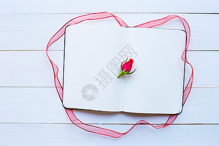 白色木质背景上带玫瑰和丝带的日记笔记本图片