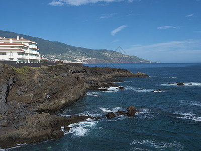 西班牙加那利群岛村的海边岩壁 海洋和绿山 蓝天背景 拉帕尔马图片