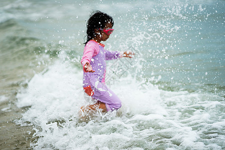 女孩在沙滩上玩海水 不停地泼水图片