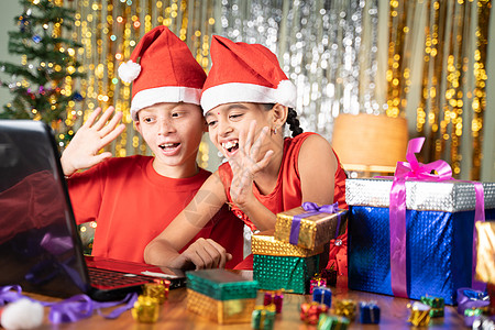 圣诞节庆祝活动期间 孩子们在装饰背景的家中通过视频通话获得了笔记本电脑前的圣诞礼物和开幕礼物图片