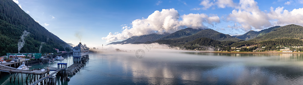 阿拉斯加加斯蒂诺海峡朱诺港和云雾缭绕的群山全景拍摄 游轮和小船停靠在港口 作为背景的蓝色多云天空图片