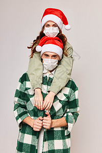 圣诞节麋鹿戴圣诞帽子的男人和女人佩戴节日医疗面具背景