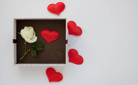 白玫瑰和巧克力有红色心脏的礼物棕色箱子和在白色背景的一朵白玫瑰 3 月 8 日情人节和母亲节的概念和生日祝福 tex 的空间背景