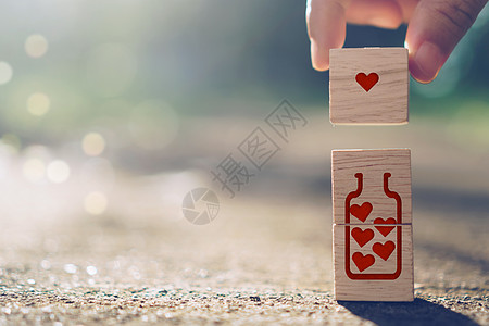 手持带有心形标志图标的木制立方体 复制空间自然阳光 您可以将文字放在背景上 情人节爱情季节 积木 庆典图片