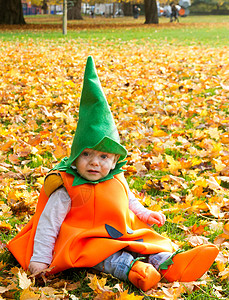 秋天一个公园的婴儿童子装扮成南瓜坐着 叶子图片