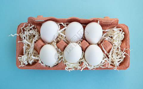 蓝色背景中米色环保纸板蛋容器中的六个白色新鲜有机鸡蛋 复活节概念 生态 零浪费 新鲜鸡蛋 包装图片