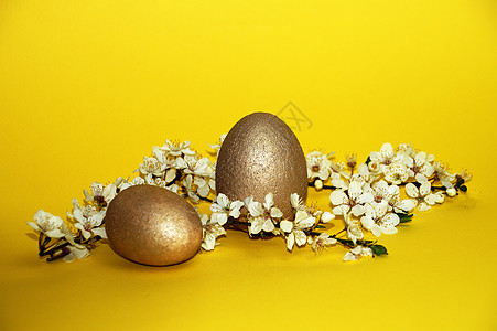 黄色台子和金蛋黄色背景复活节概念上的金蛋和花枝 白色的 礼物背景