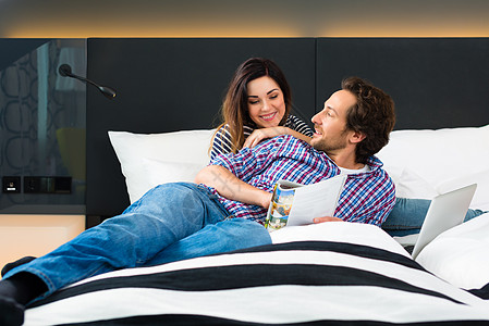 在酒店的年轻夫妇与Wifi和计算机同床共枕 年轻的 高兴图片