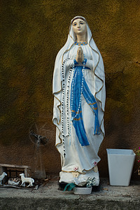 圣母玛利亚雕像是爱和善良的象征 其祭品站立在石壁上 对着棕墙图片