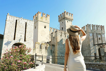 在欧洲旅行 在西尔米奥奈 Sirmione 往斯卡利格罗城堡 走的女游客的背影 在意大利加尔达湖享受参观西尔苗内的女孩的后视图图片