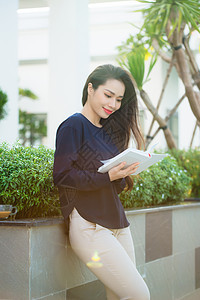 在阳光明媚的日子里 站在校园咖啡馆露台上微笑的女学生看书的画像 教育 生活方式和人们的观念 自由 放松图片