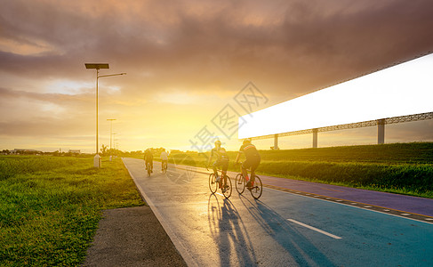 傍晚 运动员在路上骑自行车 靠近空白的广告牌 夕阳的天空 夏季户外运动健康快乐生活 骑自行车的人在自行车道上骑山地自行车图片