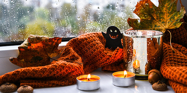 有毛衣和鬼南瓜的蜡烛 窗台上的干叶子 万圣节家庭装饰品 雨天窗户 燃烧 舒适图片