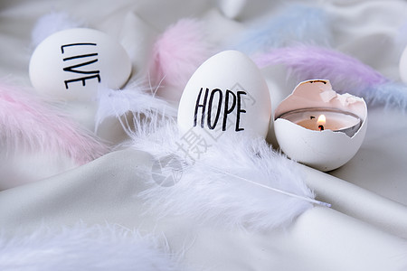 复活节彩蛋组成 复活节消息用笔画的字 桌上贝壳的大角度视图 希望 蛋壳中的蜡烛 烛光 羽毛 墙纸图片