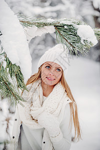 一个穿着白色衣服的女人在寒冷的冬天森林里的画像 在白雪皑皑的冬季森林里 一个头戴白帽子的女孩 快乐的 美丽图片