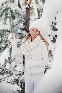 一个穿着白色衣服的女人在寒冷的冬天森林里的画像 在白雪皑皑的冬季森林里 一个头戴白帽子的女孩 季节 长的图片