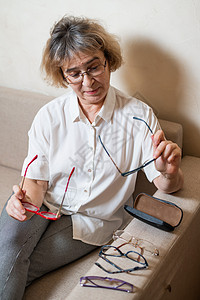 一位年长的白人妇女从她的家庭收藏中挑选眼镜 验光 退休图片