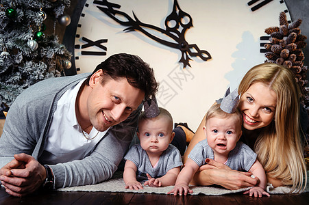 一个幸福的大家庭 有双胞胎孩子 在房子的新年室内以大钟为背景 拥抱 妻子图片