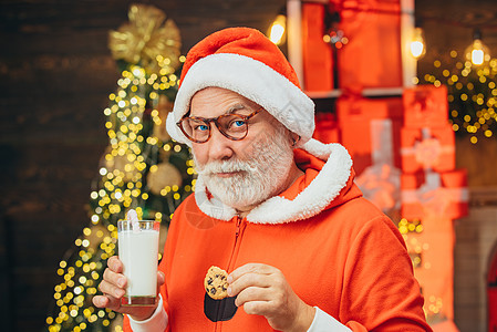 穿着圣诞老人服装的大胡子滑稽人的画像 圣诞老人的乐趣 圣诞老人在平安夜吃饼干和喝牛奶 圣诞胡子风格图片