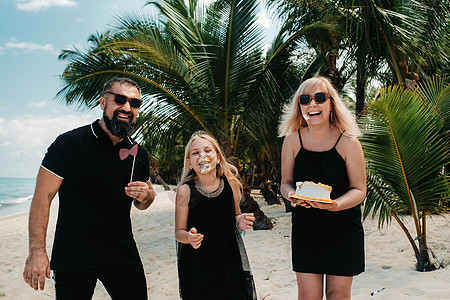 热带海滩上幸福美丽的家庭庆祝他们女儿的出生 家庭在毛里求斯岛上庆祝生日 享受 异国情调图片