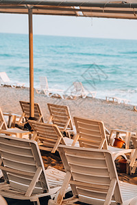 在海前面的空的太阳躺椅 在沙滩的太阳椅 大浪暴风雨天气 海边空荡荡的躺椅和折叠伞架 海景 热带图片