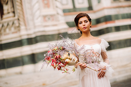 佛罗伦萨的新娘带着美丽的花朵图案作为面具 时尚的新娘穿着婚纱带着面具站在佛罗伦萨的老城区 佛罗伦萨的模特女孩 时髦 假期图片