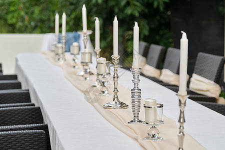 室外花园内白桌布和蜡烛台的桌子图片