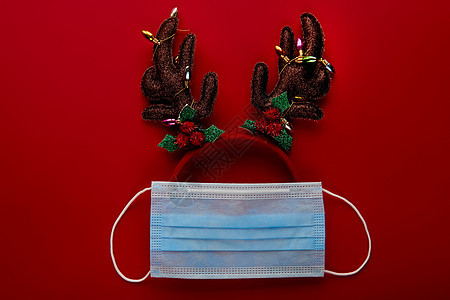 红背景面罩和装饰所制的节日冠状病毒驯鹿 平底 顶端风景圣诞假日组成 新年墙纸横幅 玩具 冷杉背景图片
