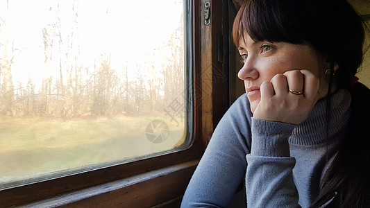 坐在窗边的经典火车上旅行的年轻漂亮女人 老式过滤器 女游客从行驶中的旧火车窗外望去 享受旅行和自然美景 照片 冒险背景图片