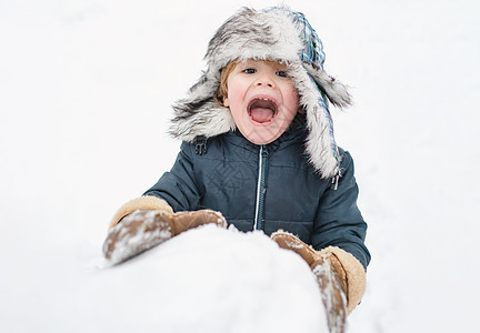 兴奋的孩子在玩雪 可爱的孩子在冬天的帽子在冬季公园玩雪球 孩子们的冬天衣服图片